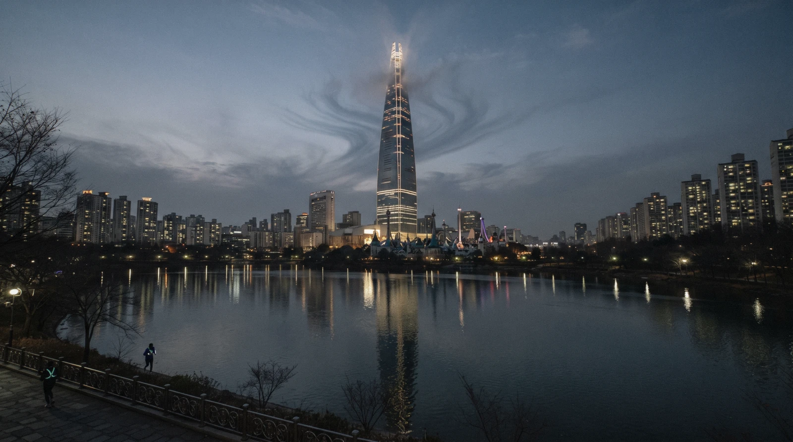 Lotte World Tower rising above Jamsil reflected in Seokchon Lake at dusk, Seoul, South Korea