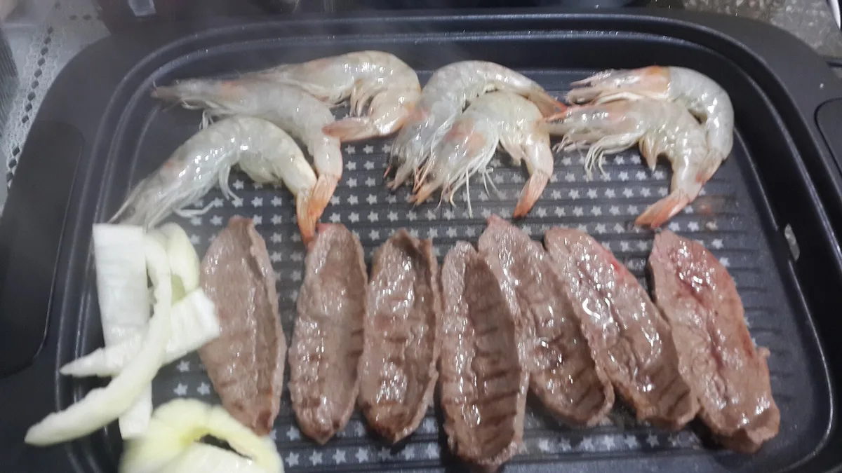 A Korean barbecue table with meat on the grill and side dishes around it, Seoul, South Korea